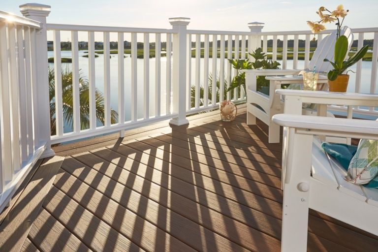A deck with a white railing and chairs overlooking a body of water.