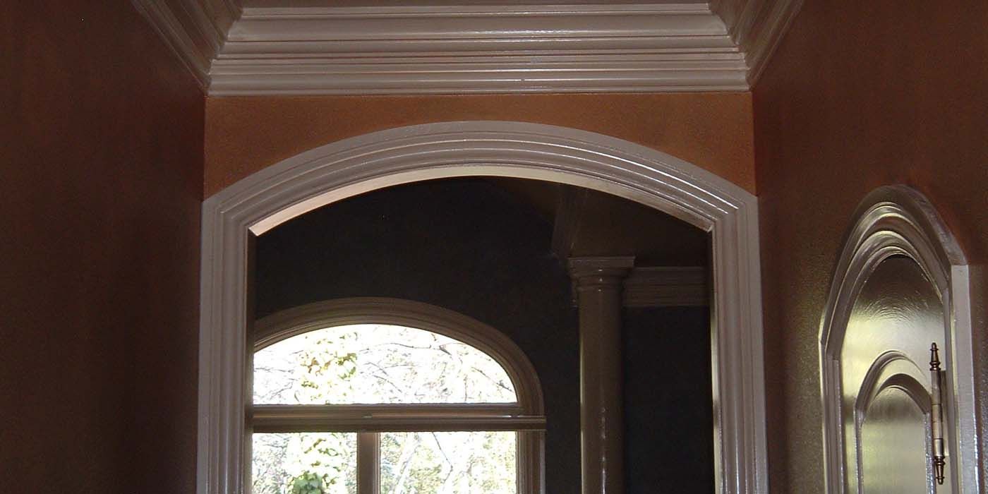 A hallway with arches and a window in a house.
