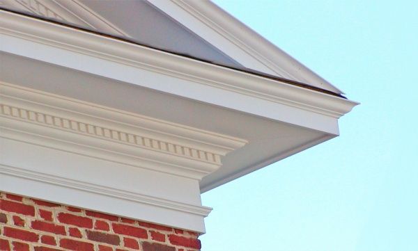 A brick building with a white trim and a blue sky in the background