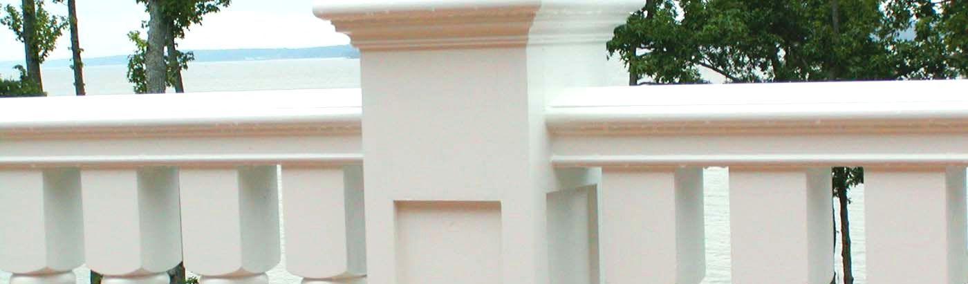 A close up of a white fence with trees in the background.
