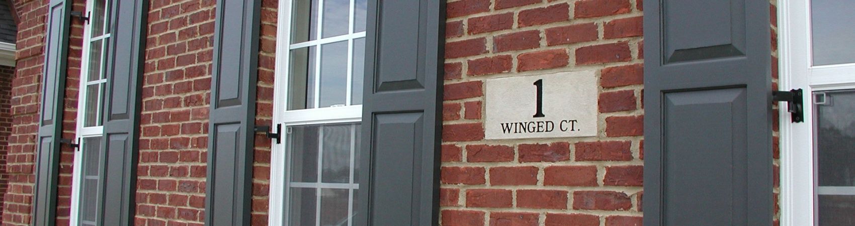 A brick building with shutters and a sign that says 1 avenue