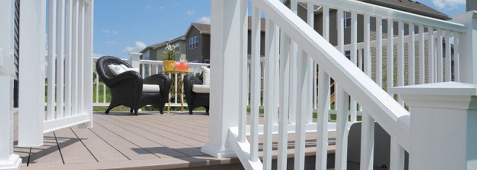A white railing leading to a deck with a table and chairs.