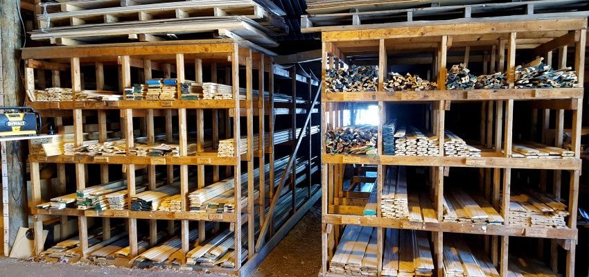 Wooden storage shelves filled with various sizes and shapes of lumber in a workshop.