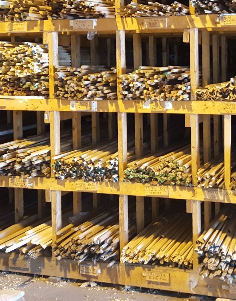 Rows of wooden beams stacked in labeled compartments at a lumberyard.