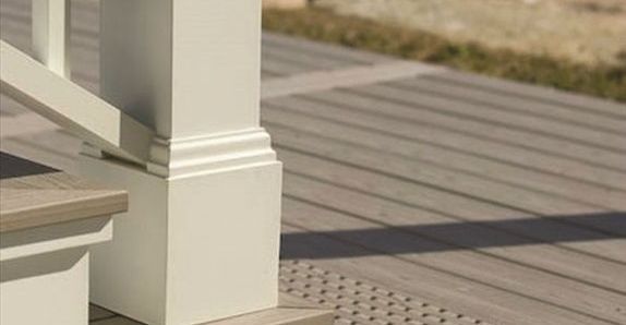 White baluster with decorative trim on a wooden deck. A railing and a step are visible.