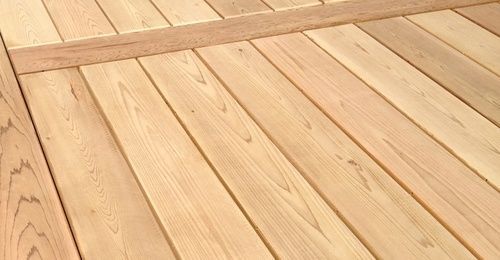 Wooden planks arranged in a pattern. Light brown wood with visible grain, assembled for a gate or door.