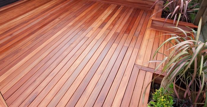 Wooden deck with a rich reddish-brown finish, with plants in a built-in planter.