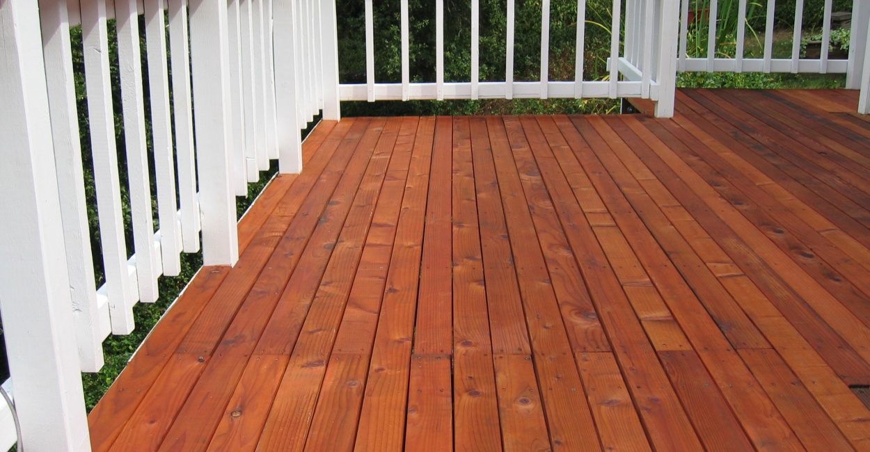 Wooden deck with white railings; the wood planks are stained reddish-brown.