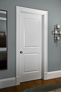 White two-panel interior door set in a white frame against a gray wall. A black doorknob is visible.
