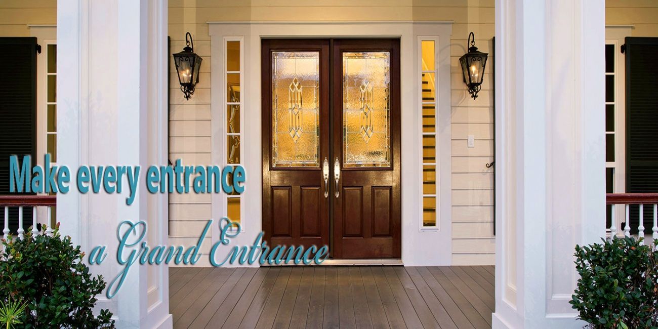 Double front doors with glass panes. The door is brown, with side lights and is framed by white pillars.