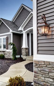 A house exterior with gray siding, stone accents, a concrete pathway, and a decorative lamp.