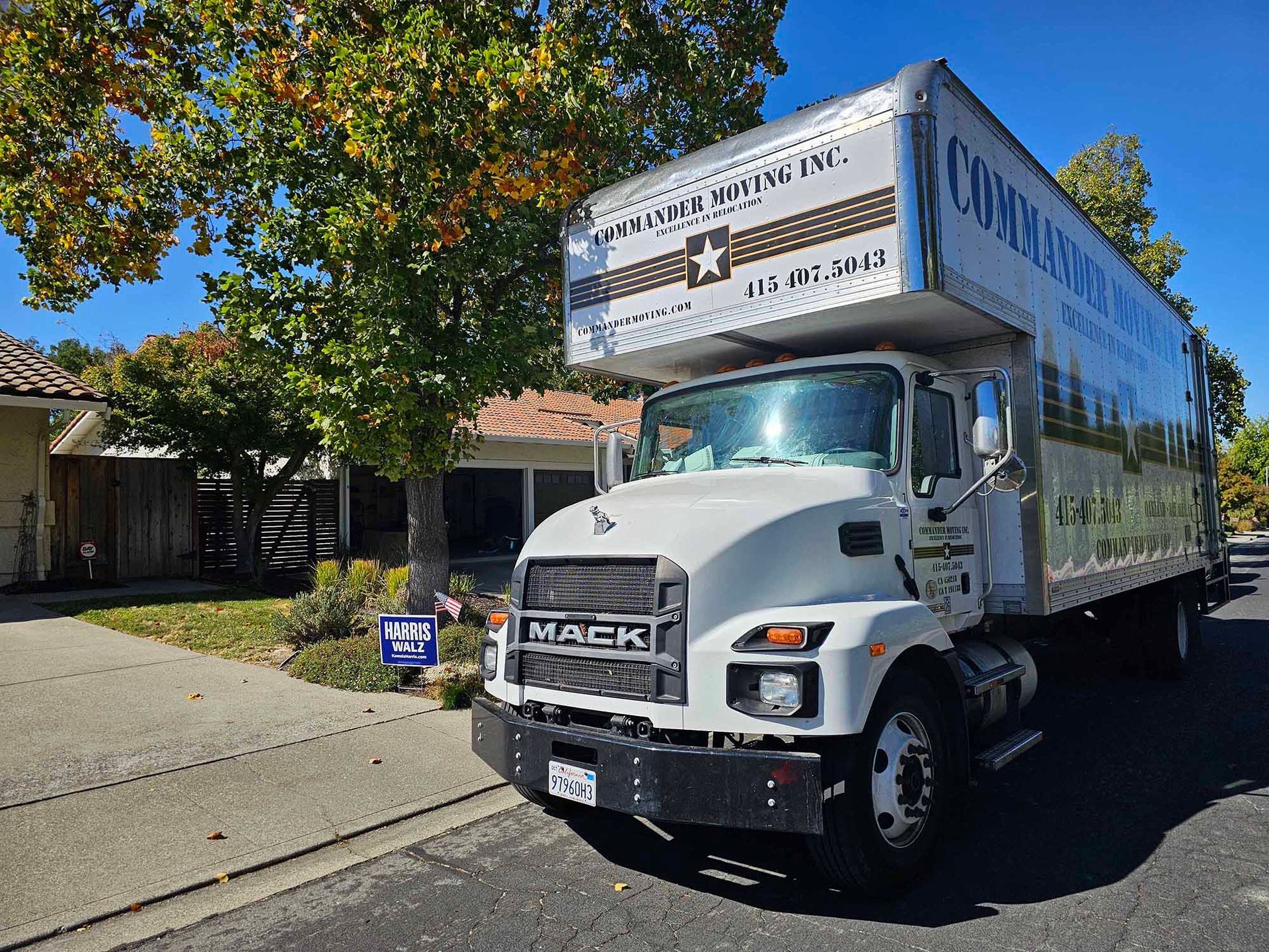 White moving truck parked on suburban street in front of a house.