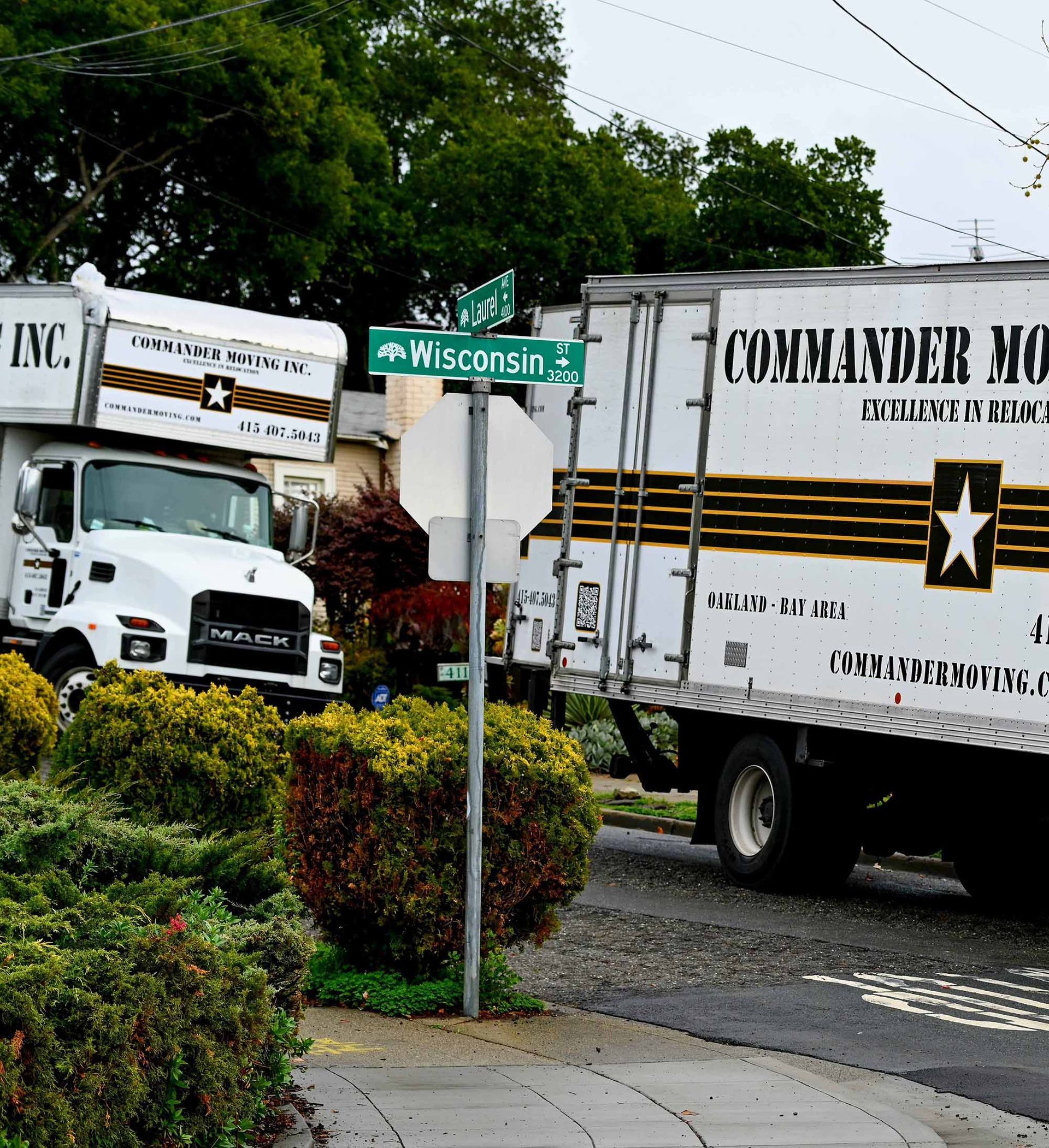 Two moving trucks parked on a residential street. One reads 