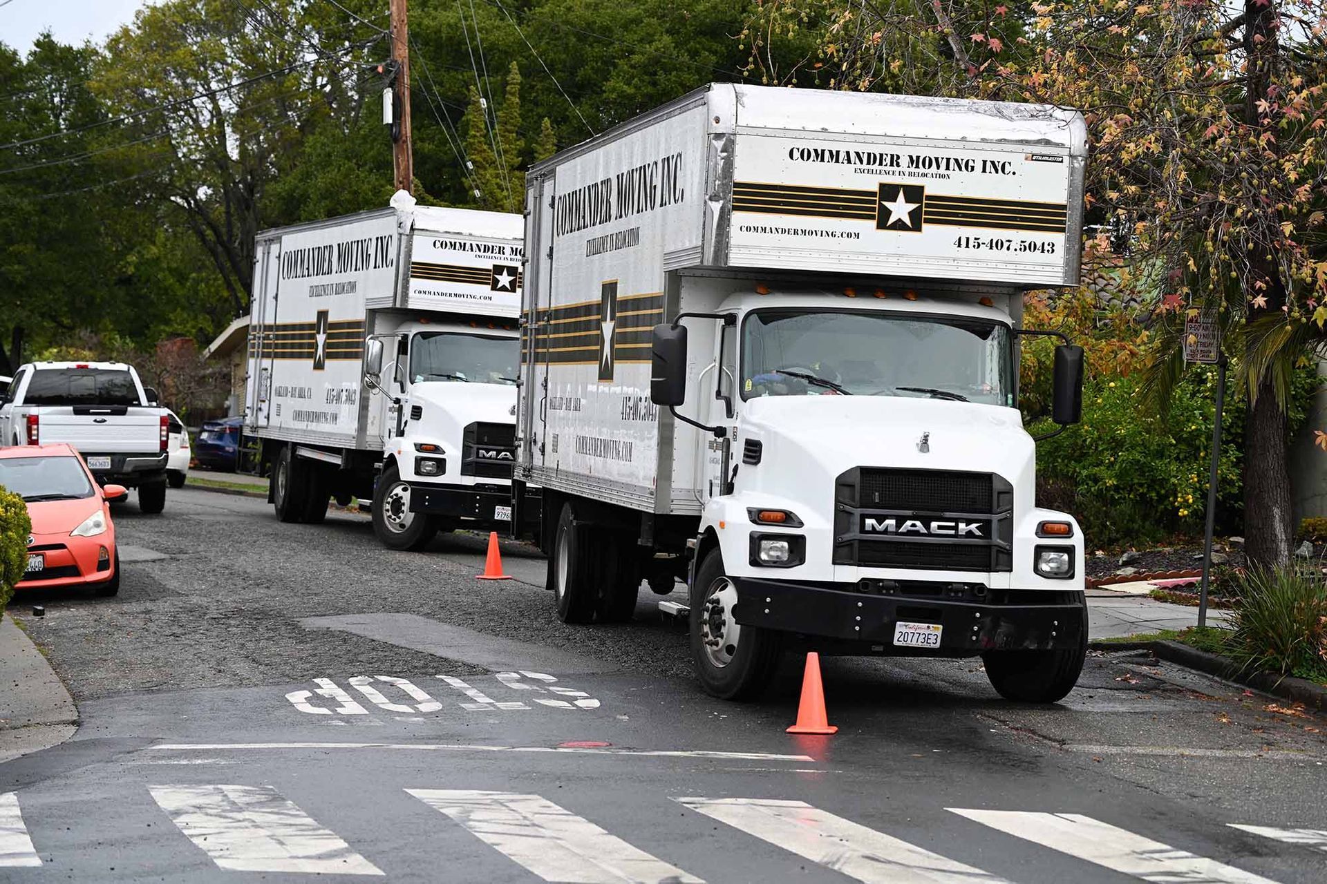 Three white moving trucks parked on a street, one labeled