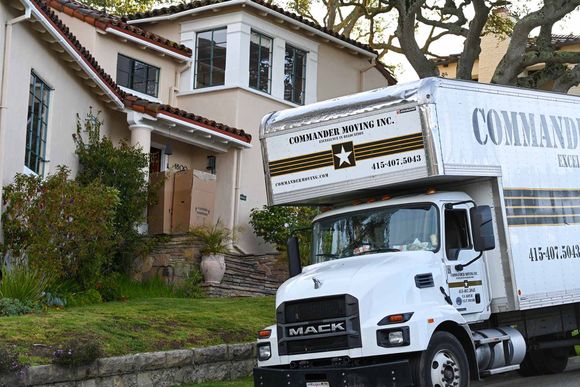 Moving truck parked in front of a house; truck is labeled