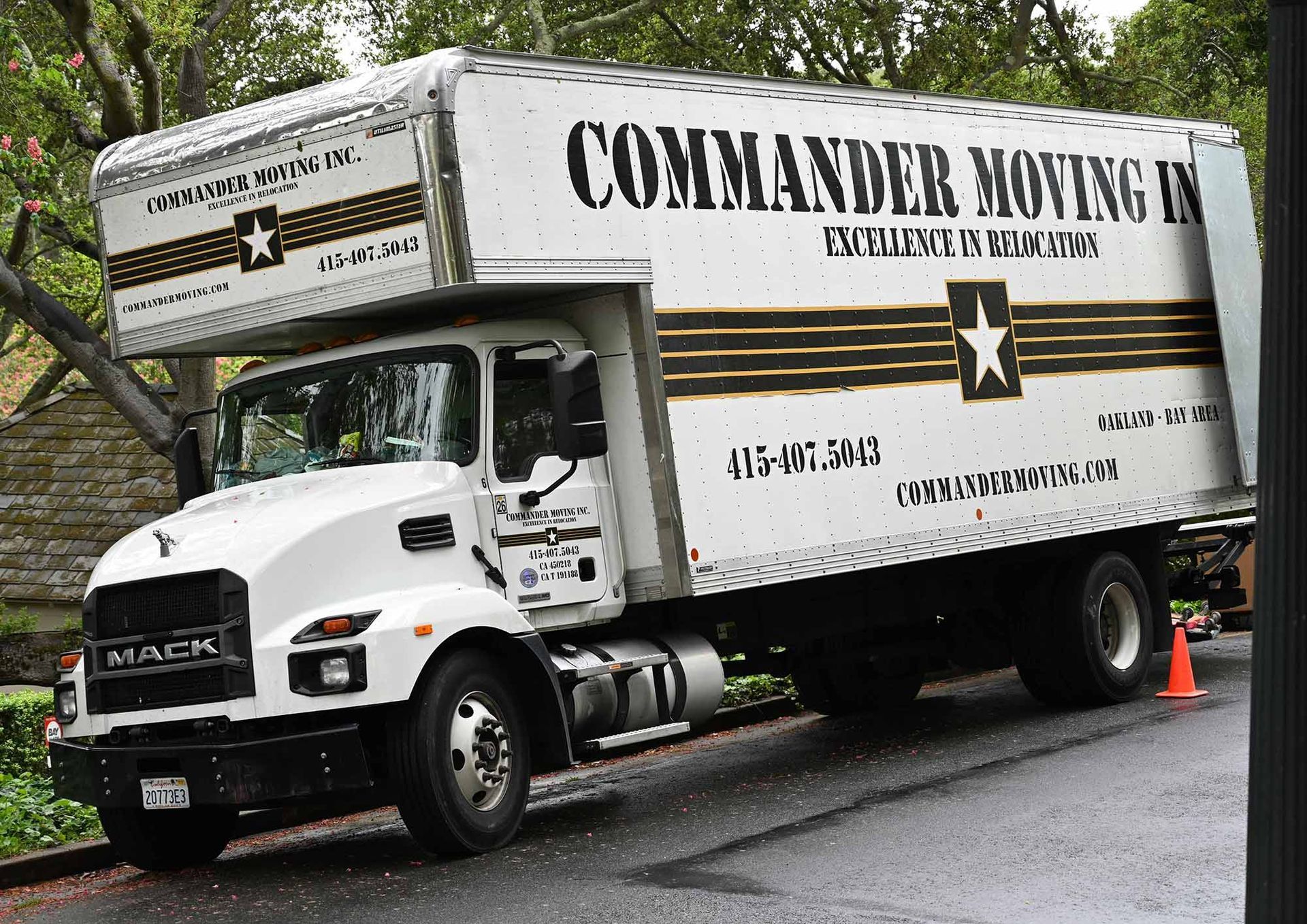 White Commander Moving truck parked on a street; military logo and company info displayed.