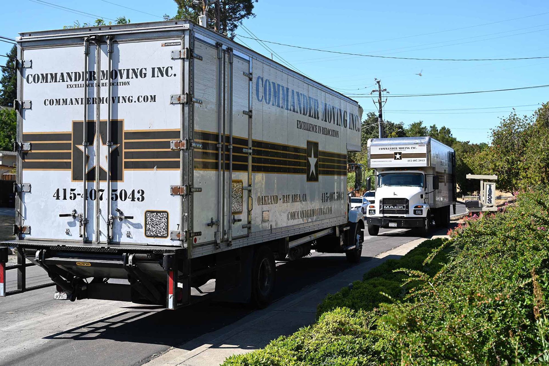 Two semi-trucks on a road, one large trailer in front, and another visible behind it.