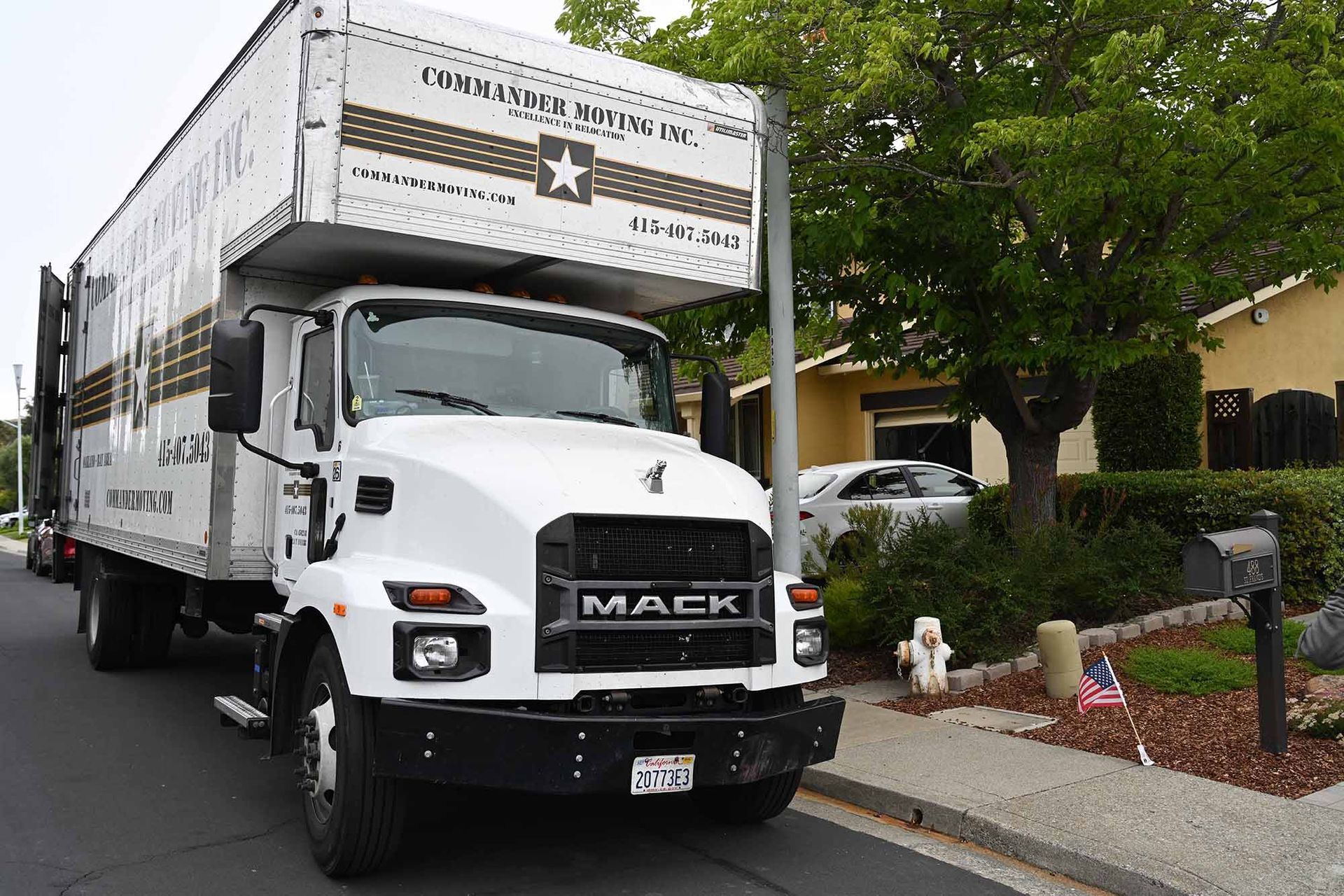White Mack moving truck parked in front of a house, preparing for a move.