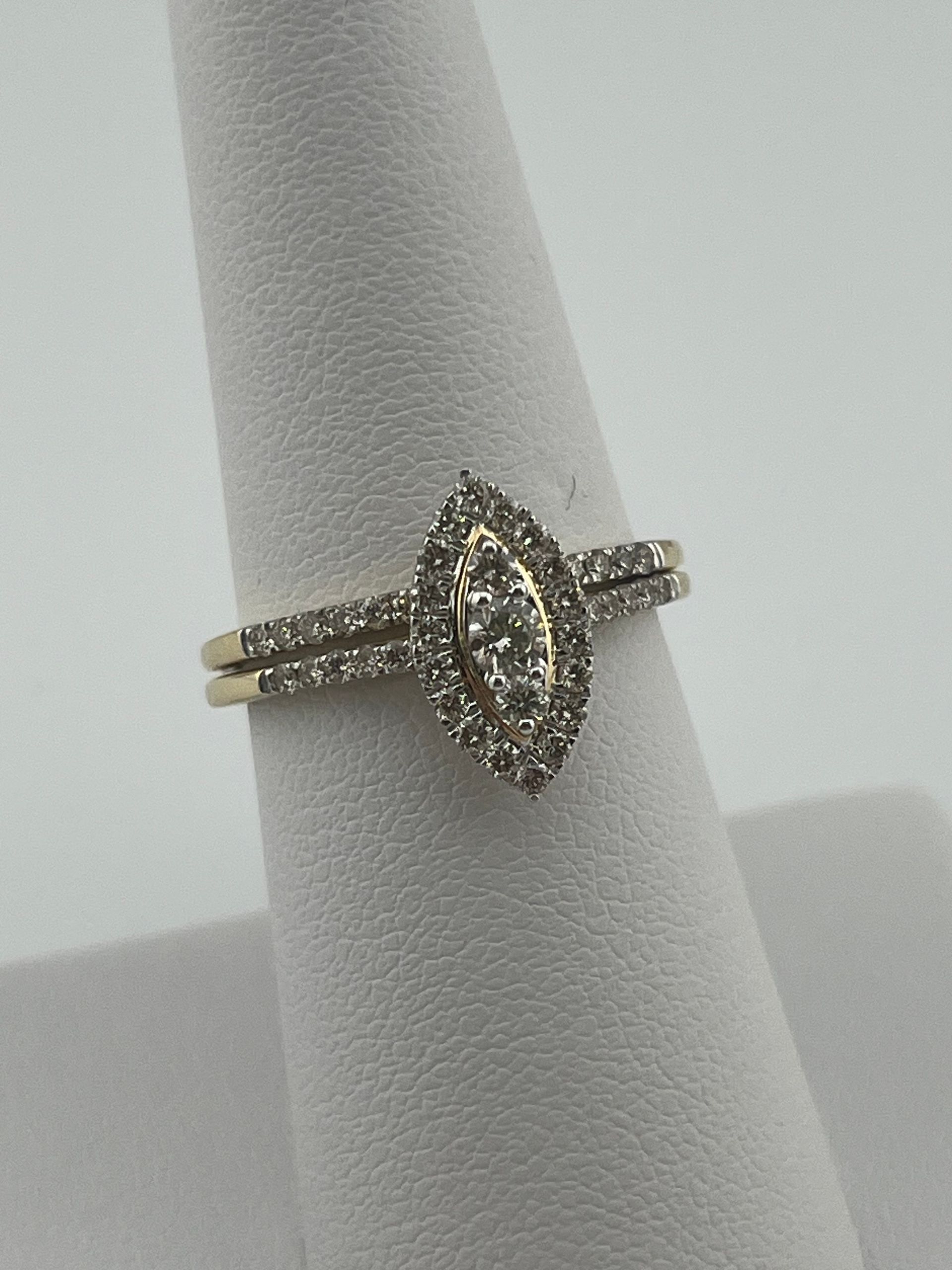 Marquise diamond ring with a pavé band on a gray display stand.