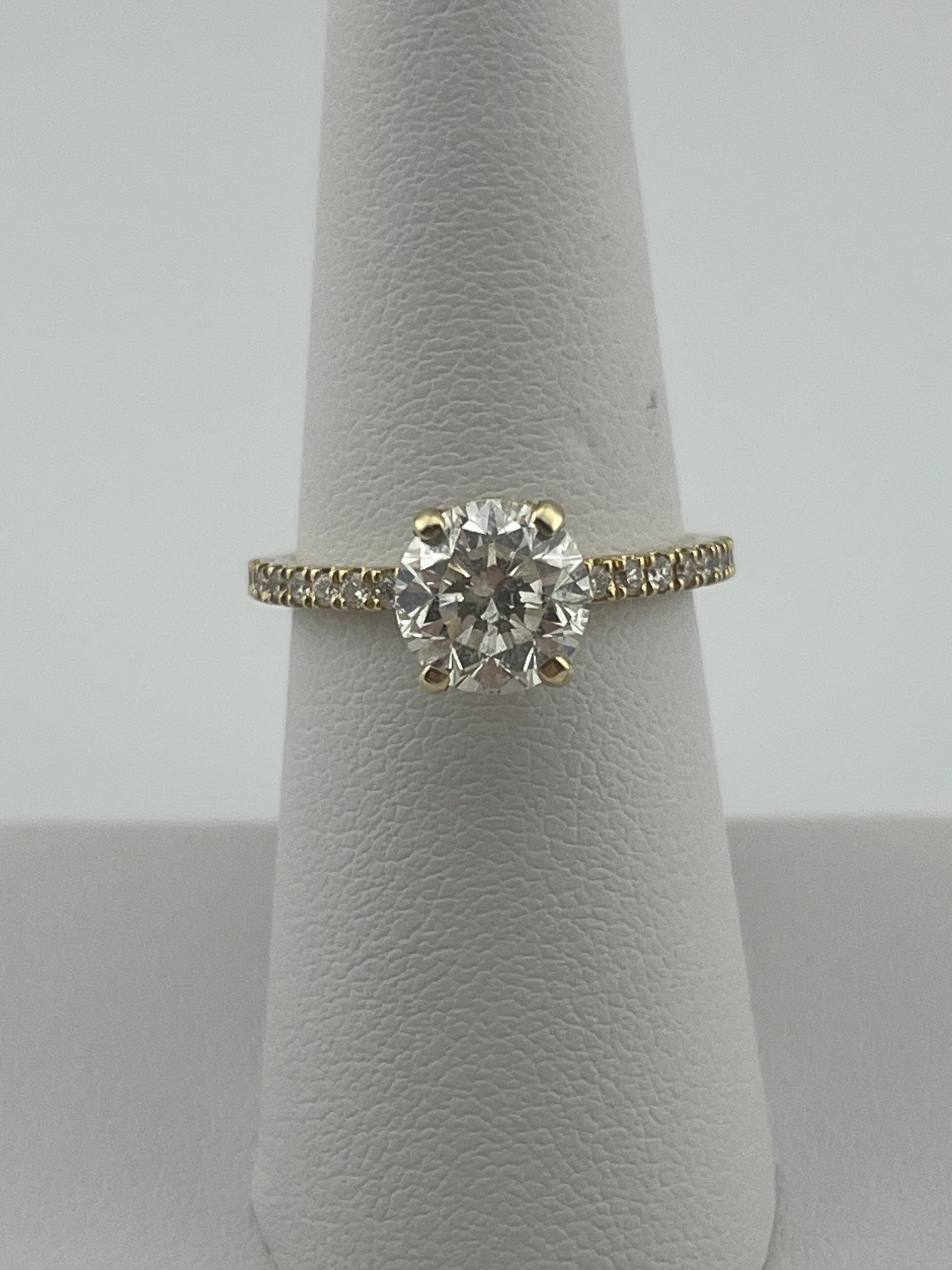 Gold and silver diamond ring on a gray display cone.