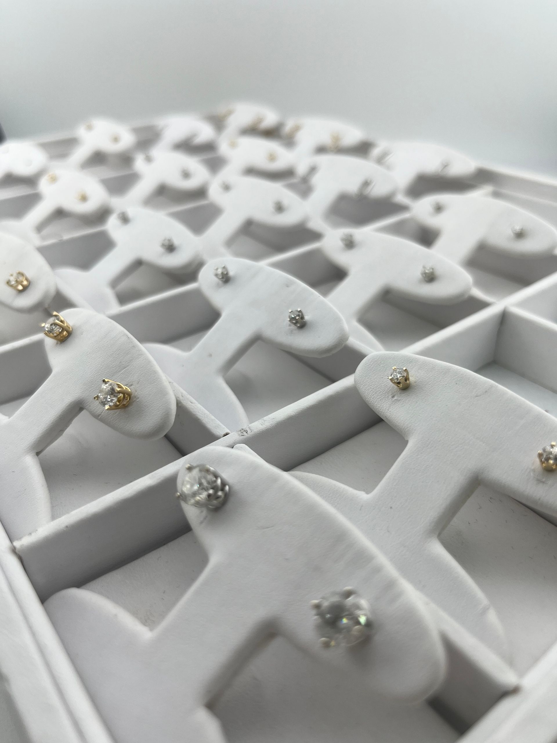 White lattice tray holding small white and silver jeweled clips or pins arranged in rows.