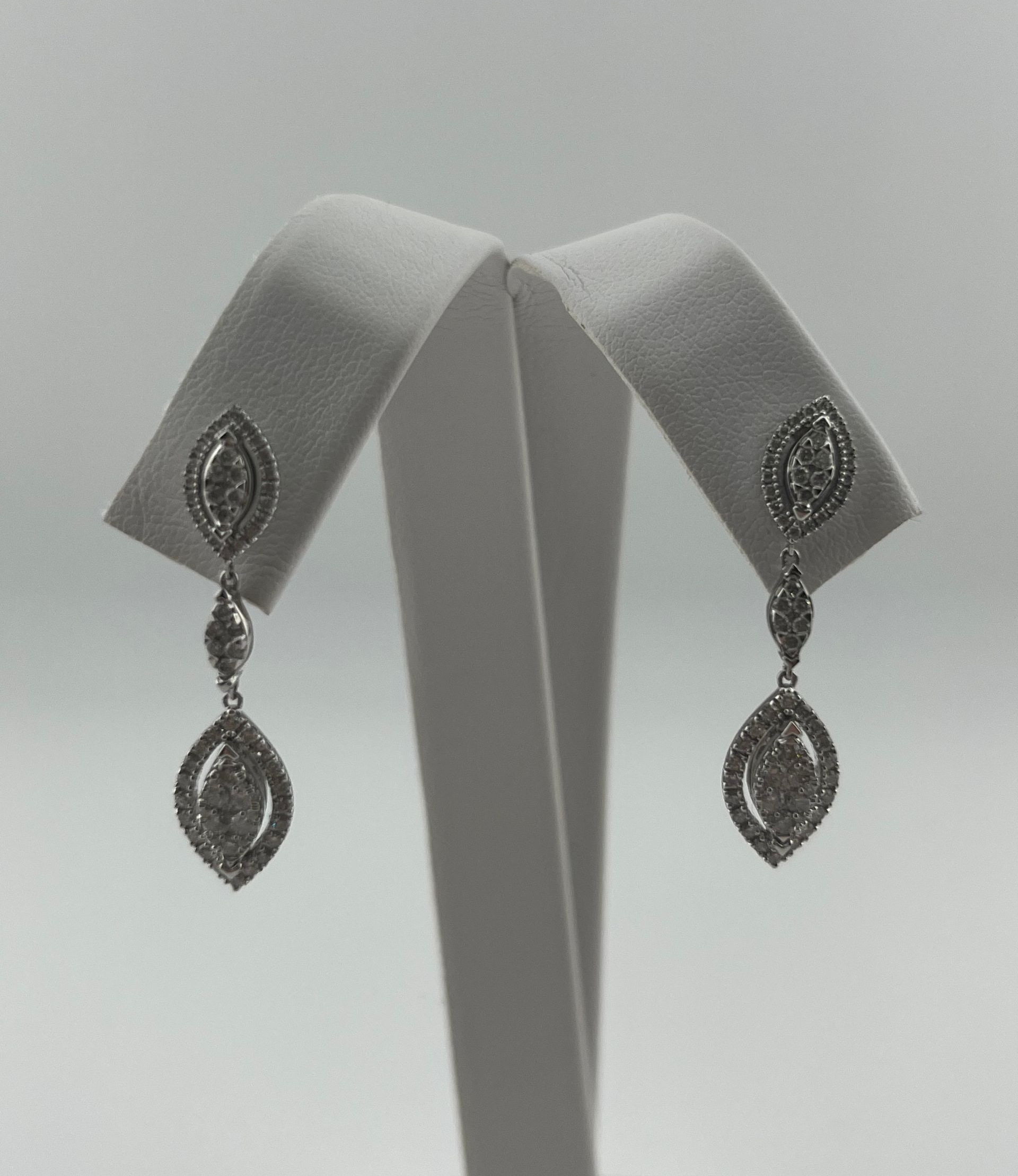 Pair of silver dangling earrings displayed on a gray jewelry stand.