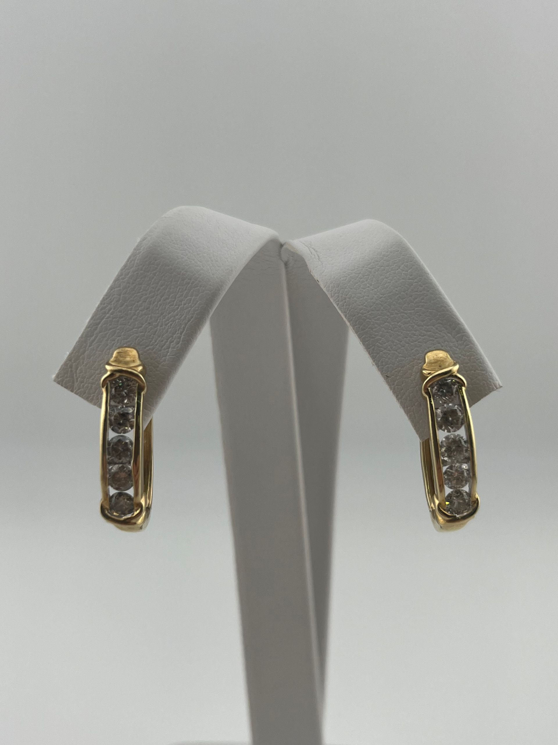 Pair of gold-and-silver dangling earrings displayed on a white stand against a light gray background.