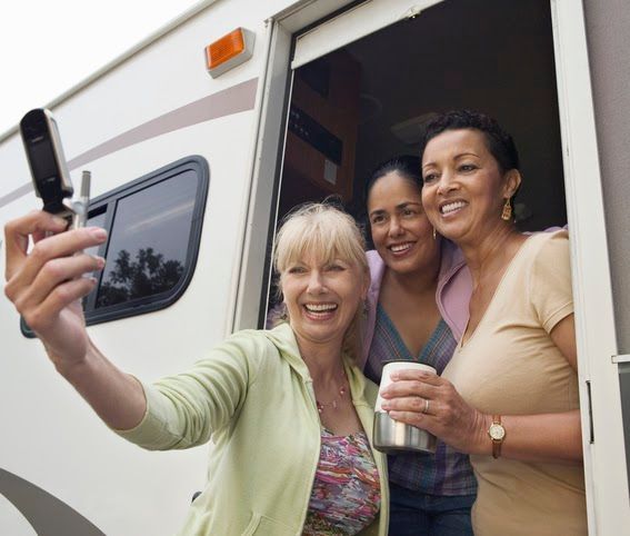 Three women are taking a selfie in front of a rv