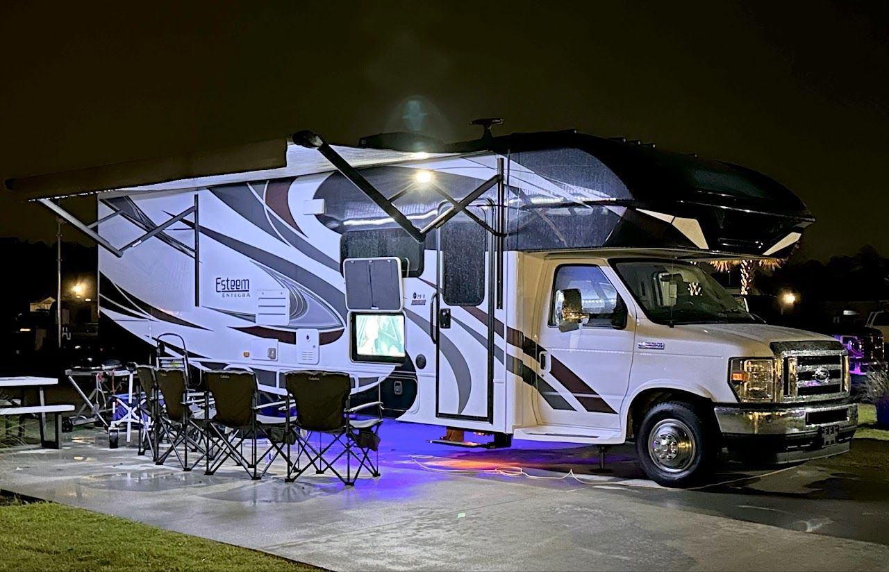 A white rv is parked in a parking lot at night.