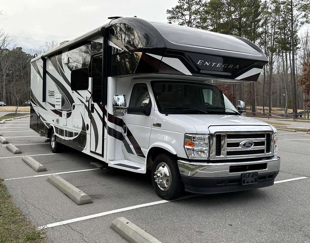 A white and black rv is parked in a parking lot.