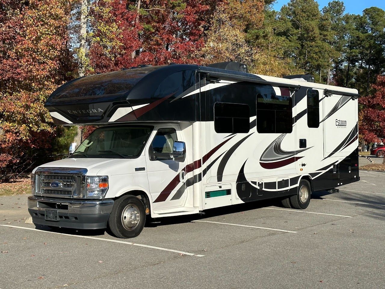 A white and black rv is parked in a parking lot.