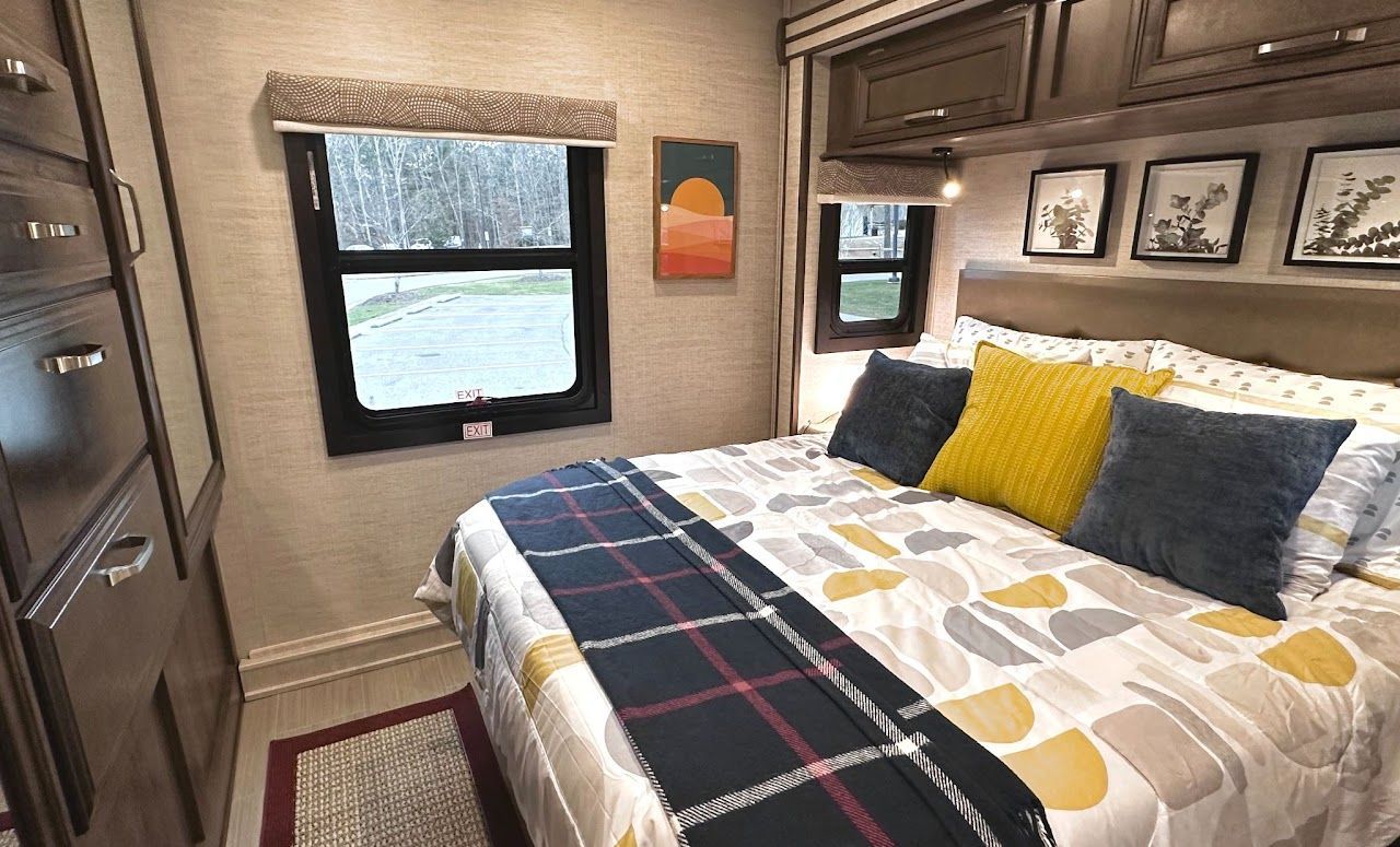 A bedroom in a rv with a bed and a window.