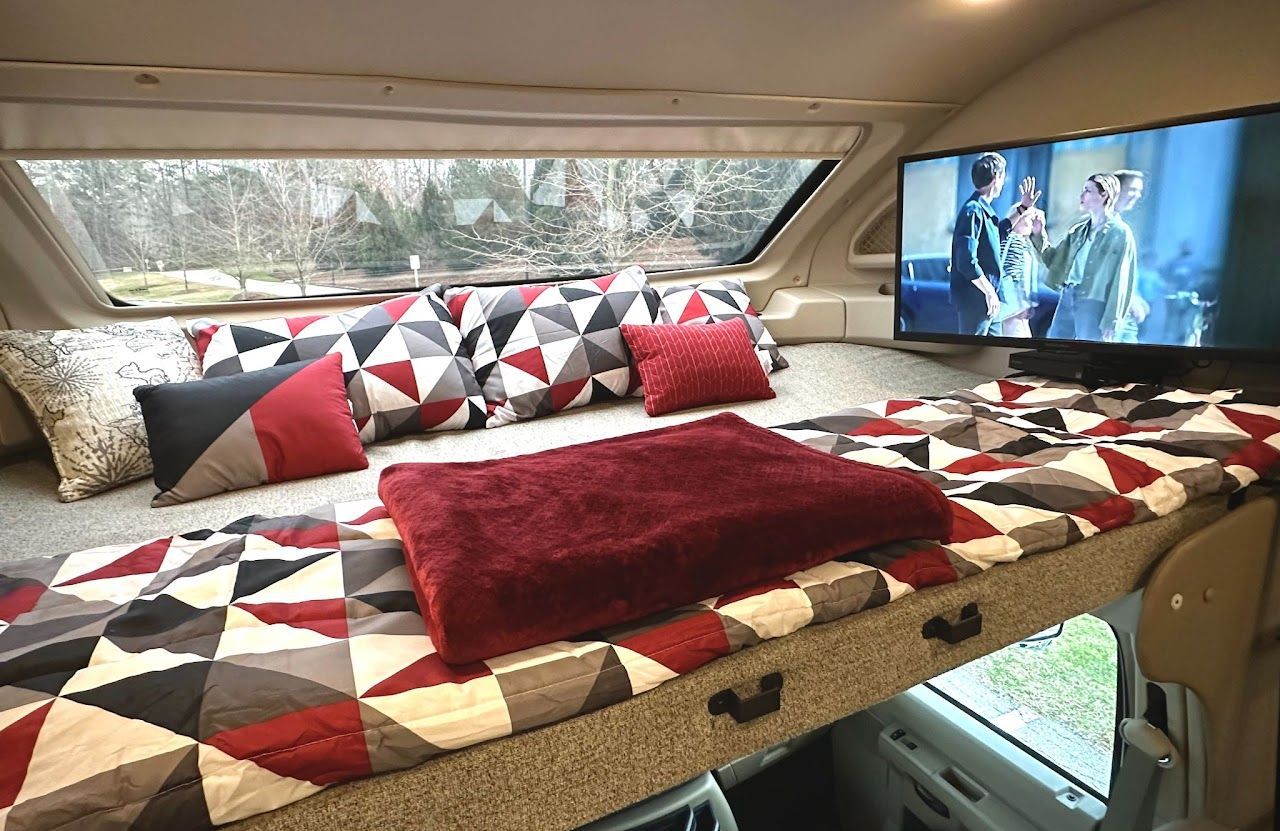 A bed with pillows and a television in a camper.