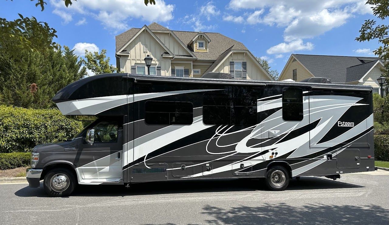 A black and white rv is parked in front of a house