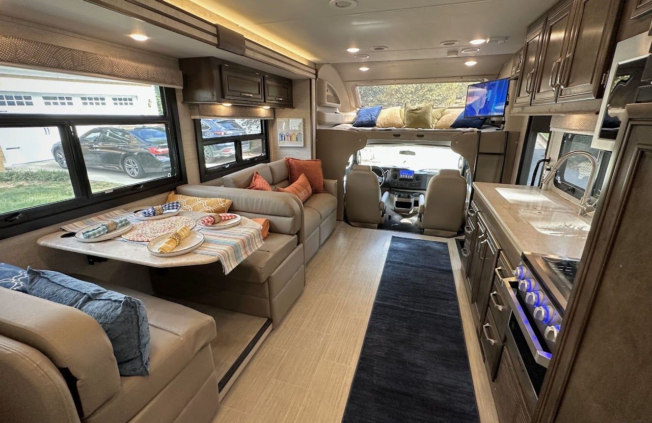 The inside of a rv with a couch, table, and television.