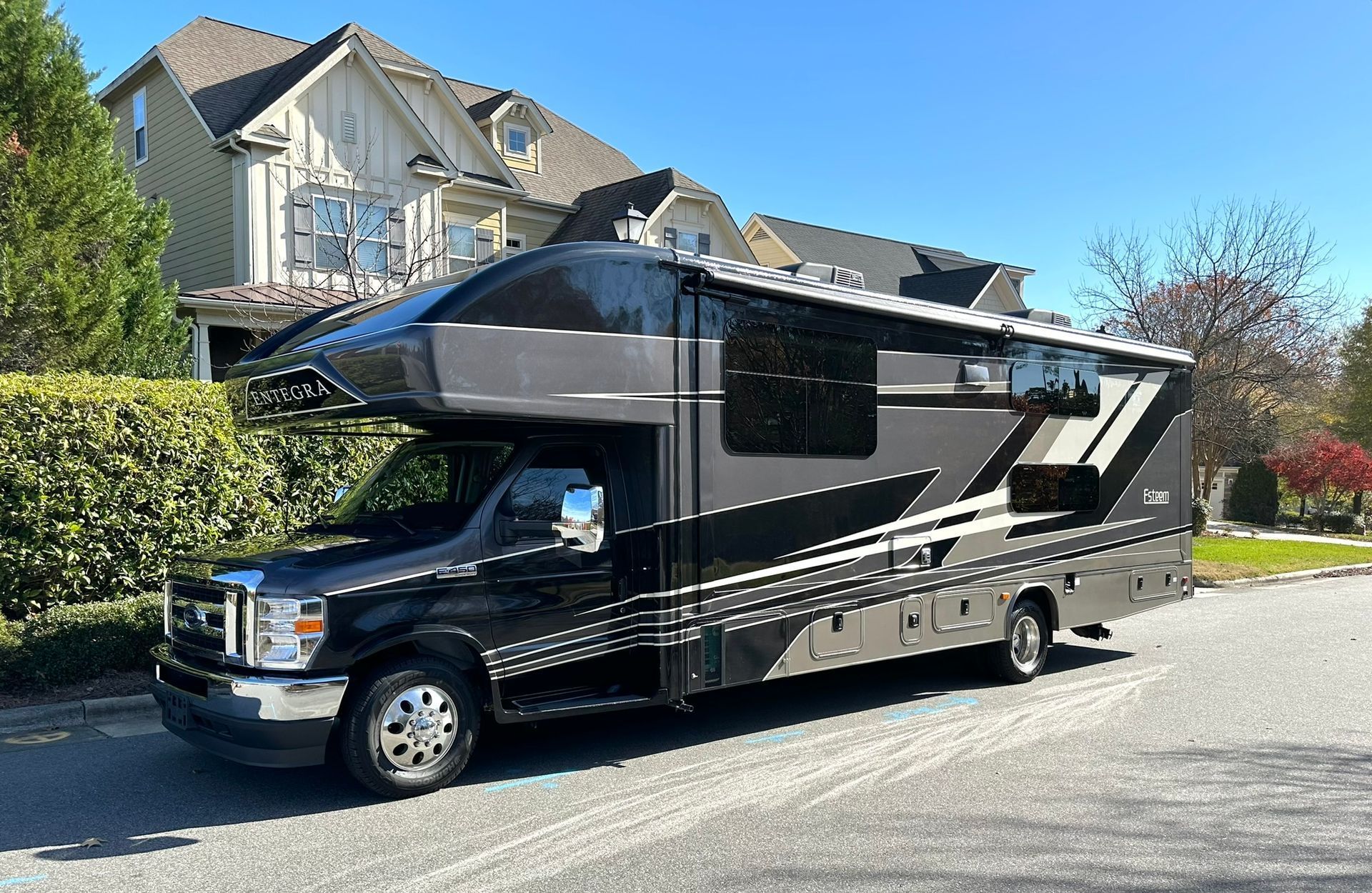 A black rv is parked in front of a house.
