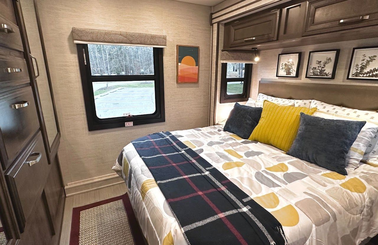 A bedroom in a rv with a bed and a window.