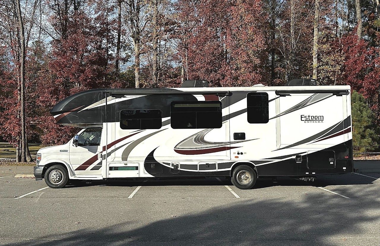 A white and black rv is parked in a parking lot.