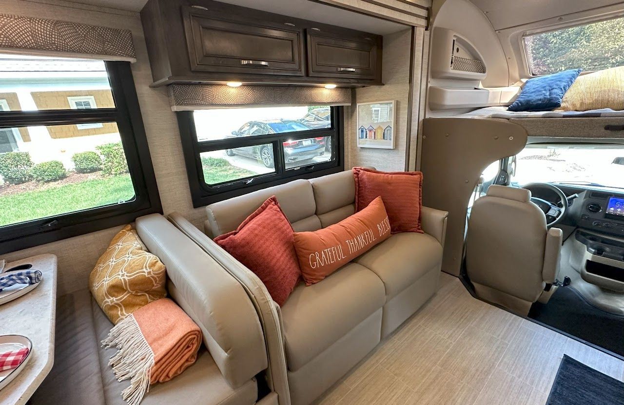 The inside of a rv with a couch and pillows.