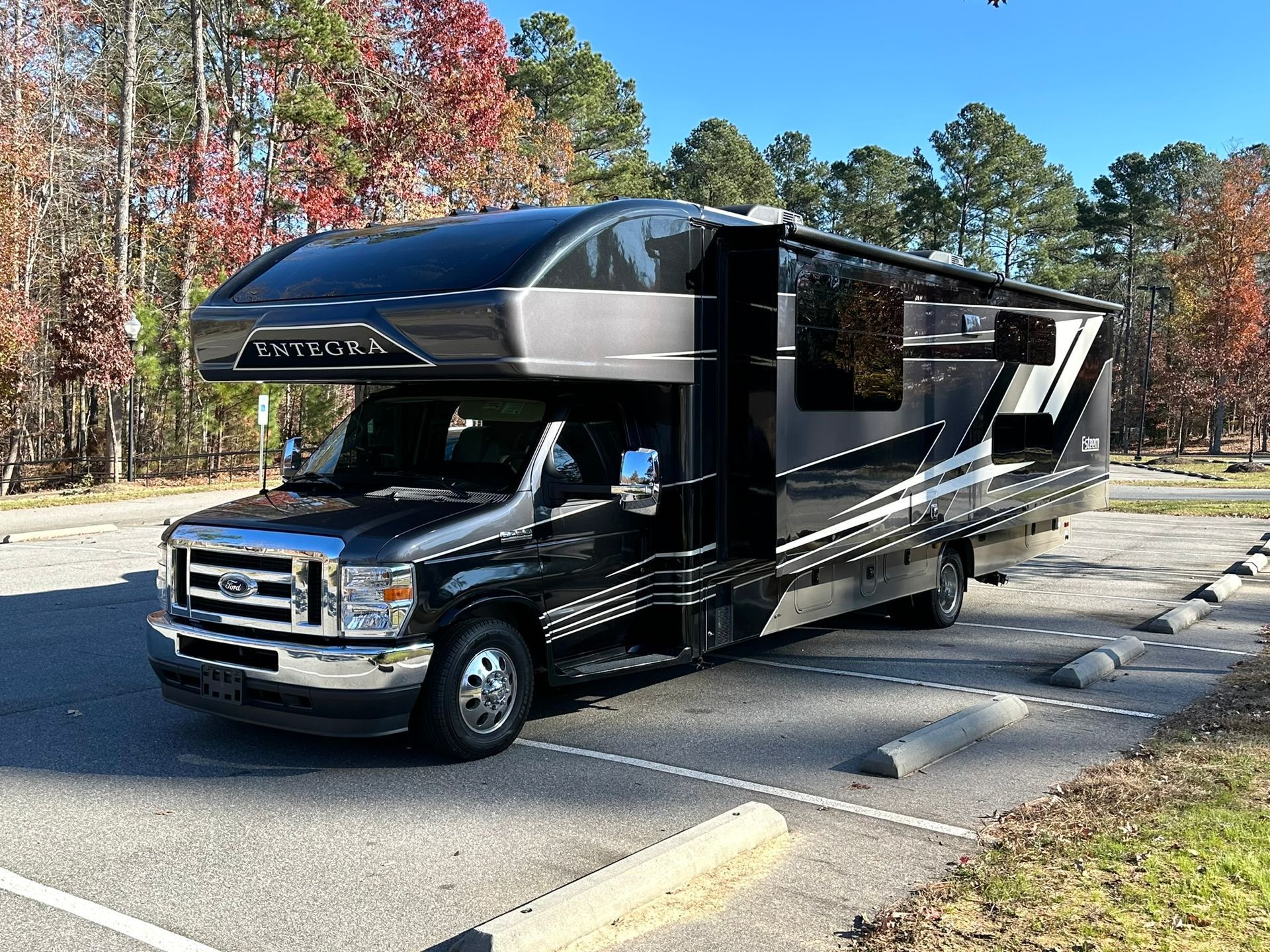 A black rv is parked in a parking lot.