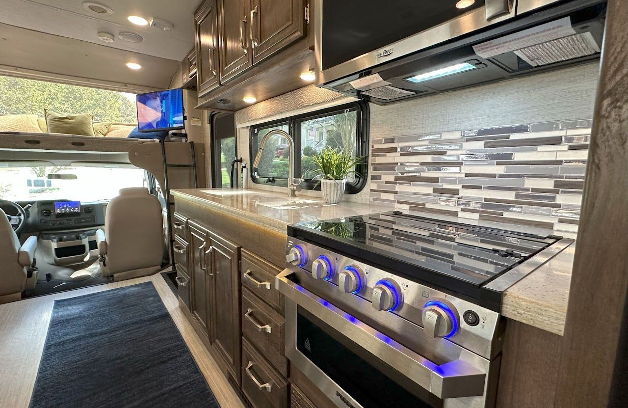 A kitchen in a rv with a stove and a sink.