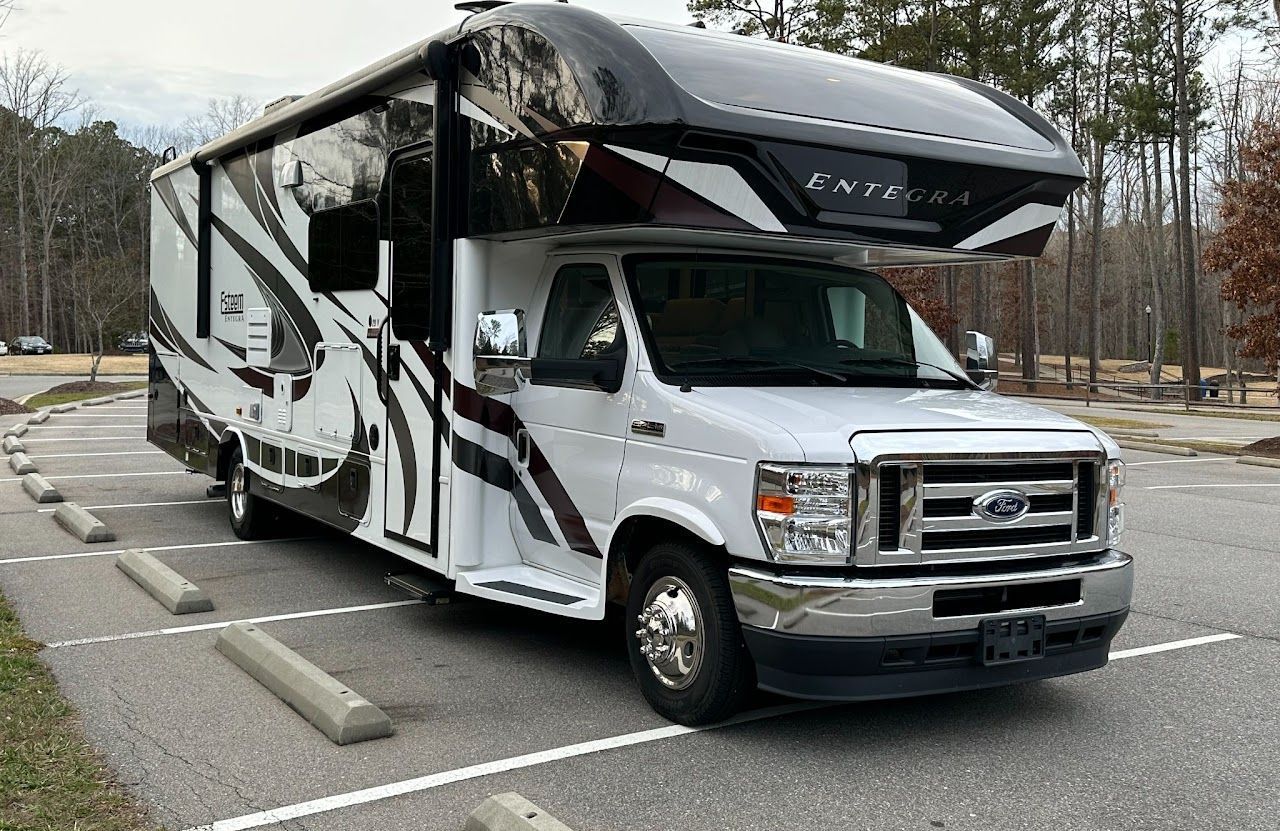 A white and black rv is parked in a parking lot.