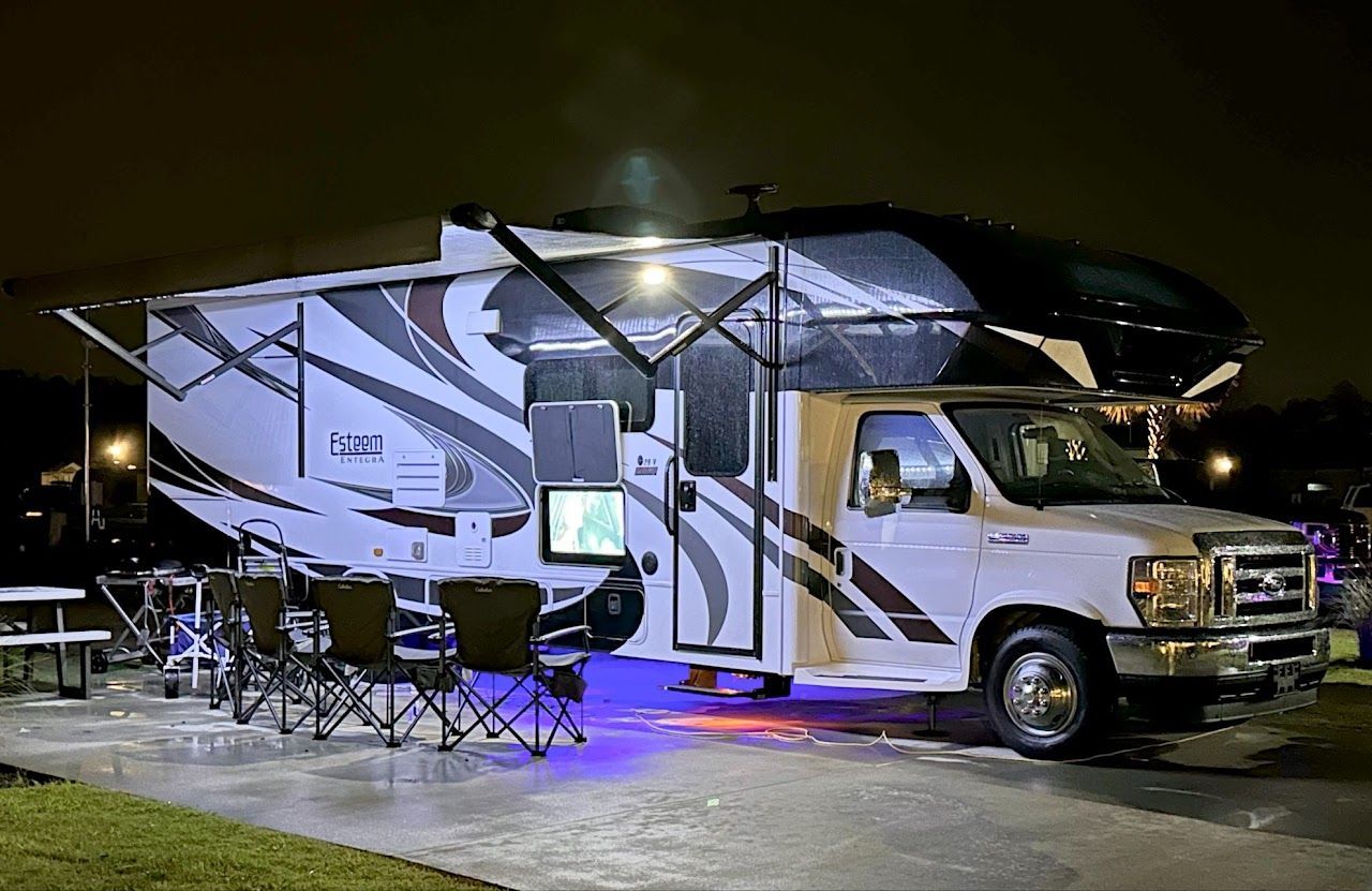 A white rv is parked in a parking lot at night.