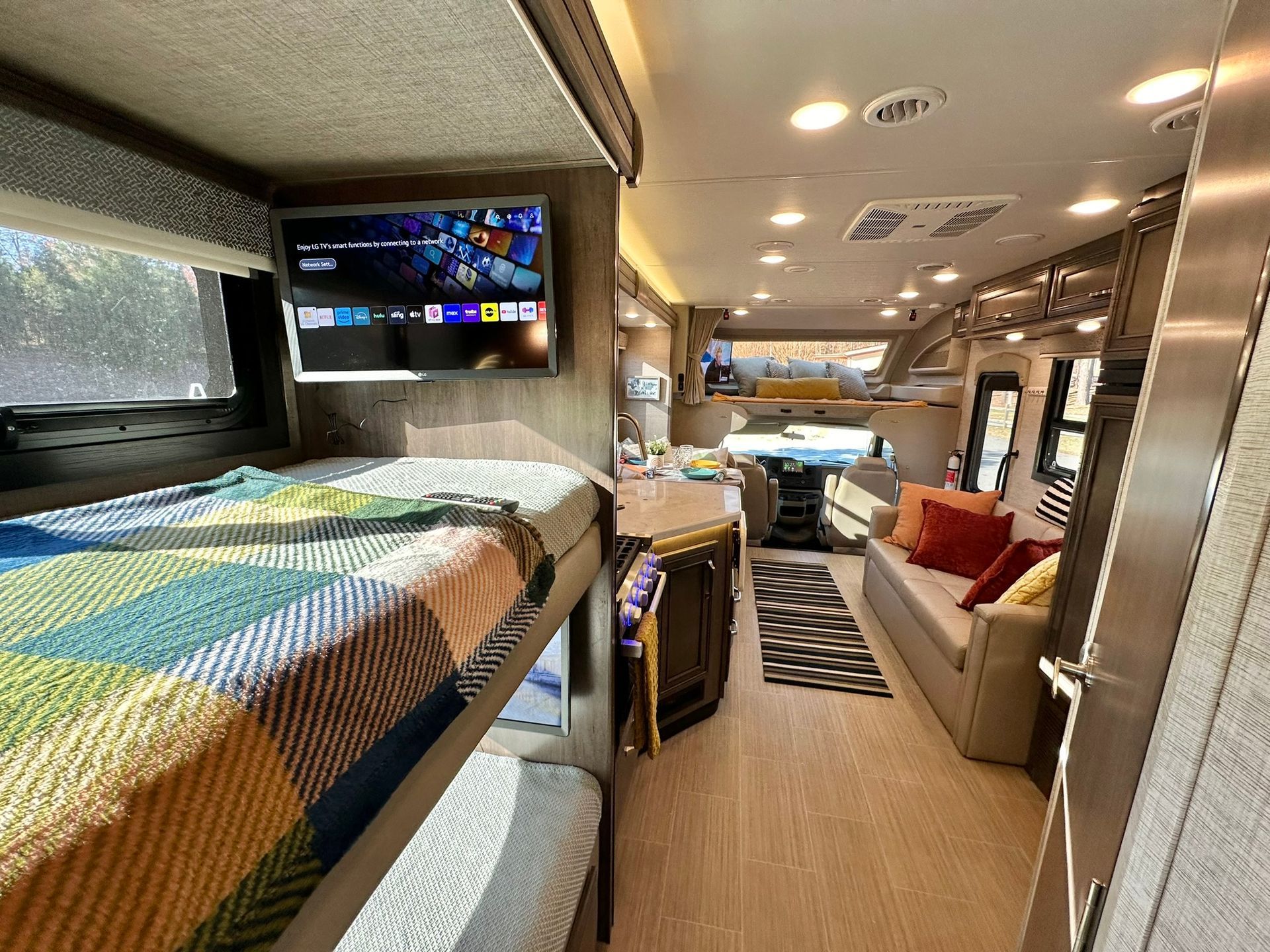 The inside of a rv with bunk beds and a flat screen tv.