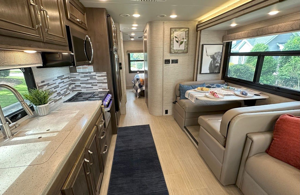 The inside of a rv with a kitchen , dining room , and living room.