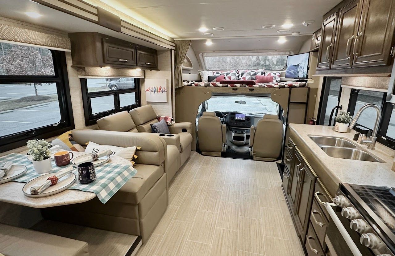 The inside of a rv with a couch , table and sink.