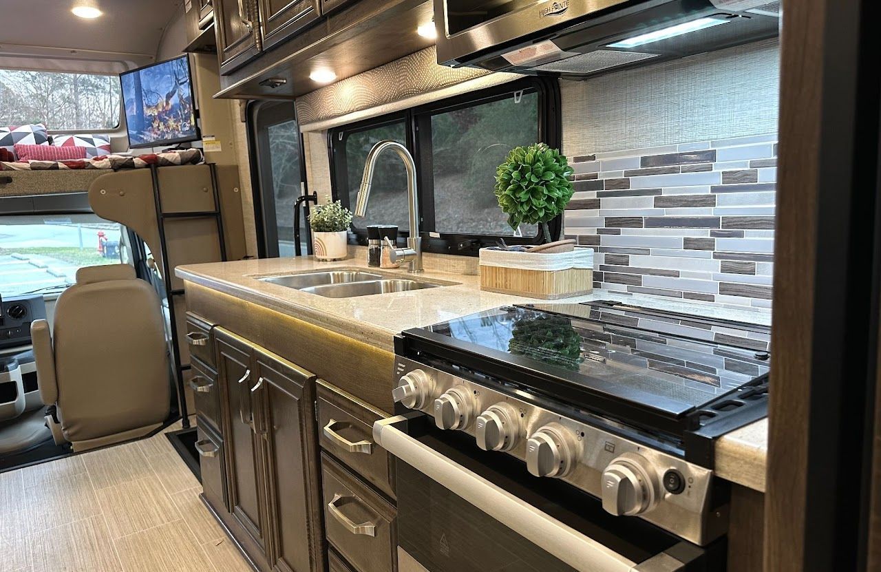 A kitchen in a rv with a stove and sink.