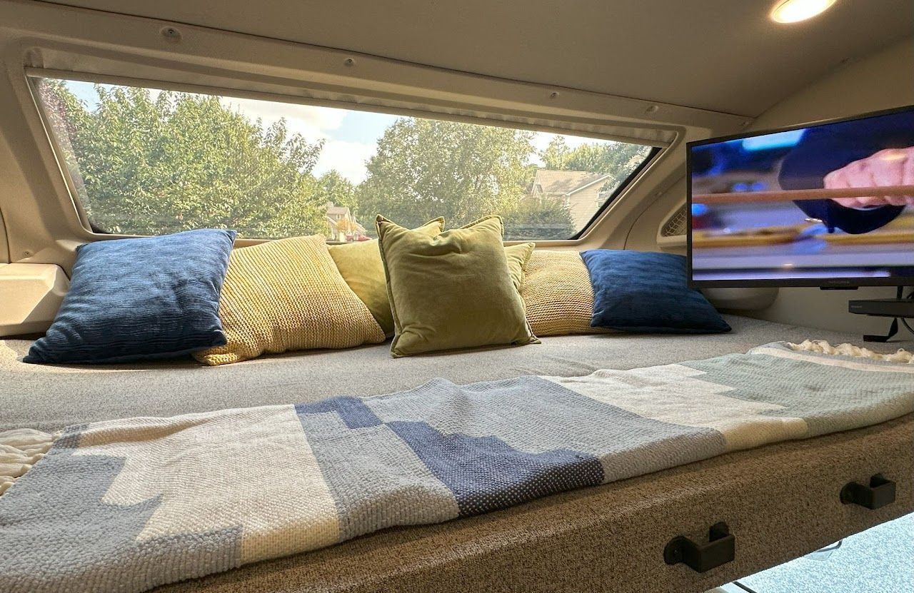 A bed with pillows and a television on the wall.