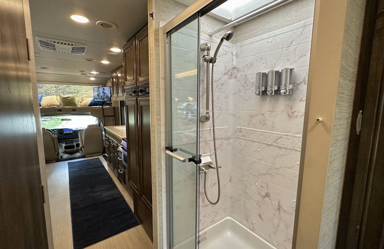 A bathroom in a rv with a shower and a sliding glass door.