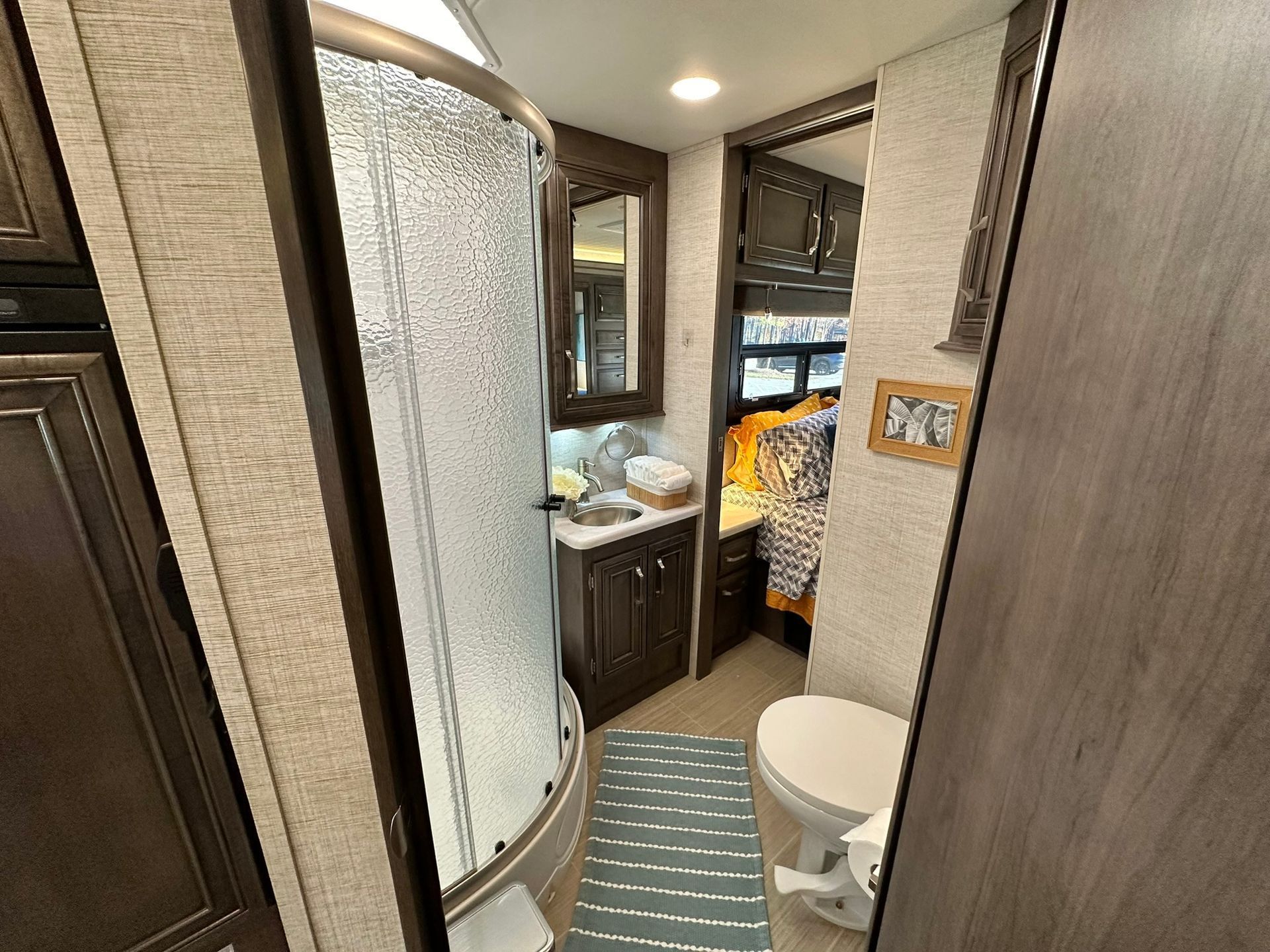 A bathroom in a rv with a toilet , sink and shower.